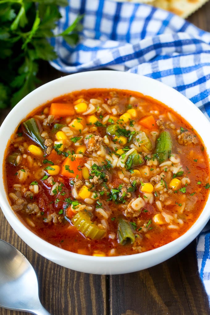 A bowl of alphabet soup with beef and vegetables in a tomato broth.