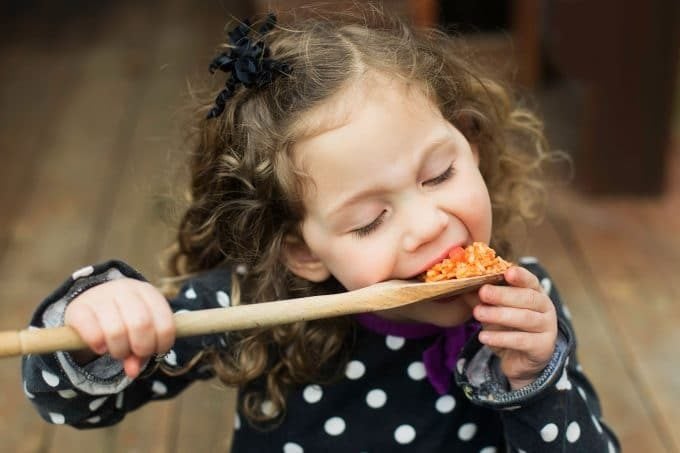 A child eating a spoonful of Mexican rice.