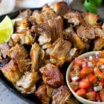 A skillet of pork carnitas served with fresh salsa.