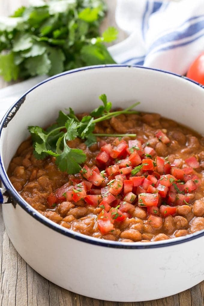 A pot of pinto beans topped with diced tomatoes and cilantro.