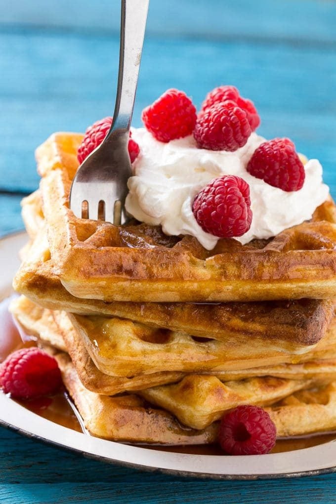 A fork in a stack of yeast raised waffles.