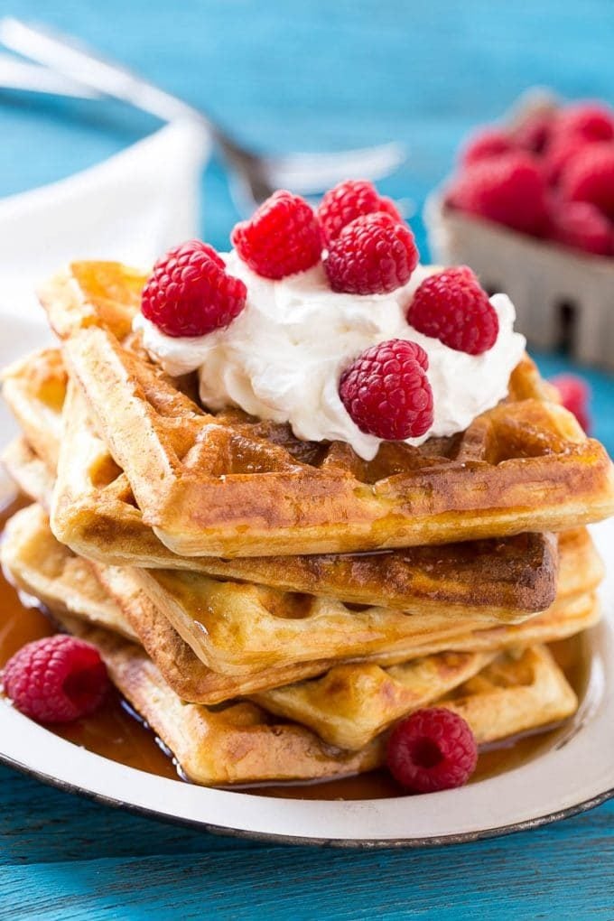 Overnight waffles garnished with whipped cream and raspberries.