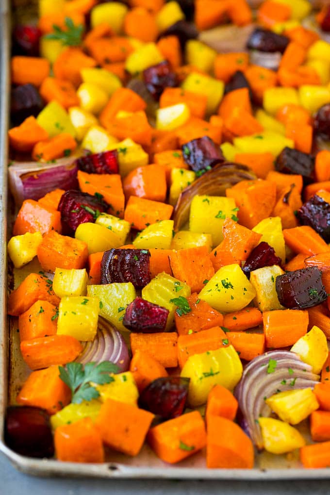 Roasted root vegetables on a sheet pan, topped with chopped parsley.