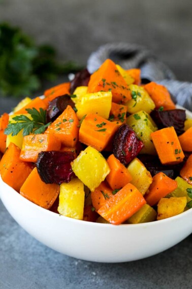 A bowl of diced roasted root vegetables topped with parsley.