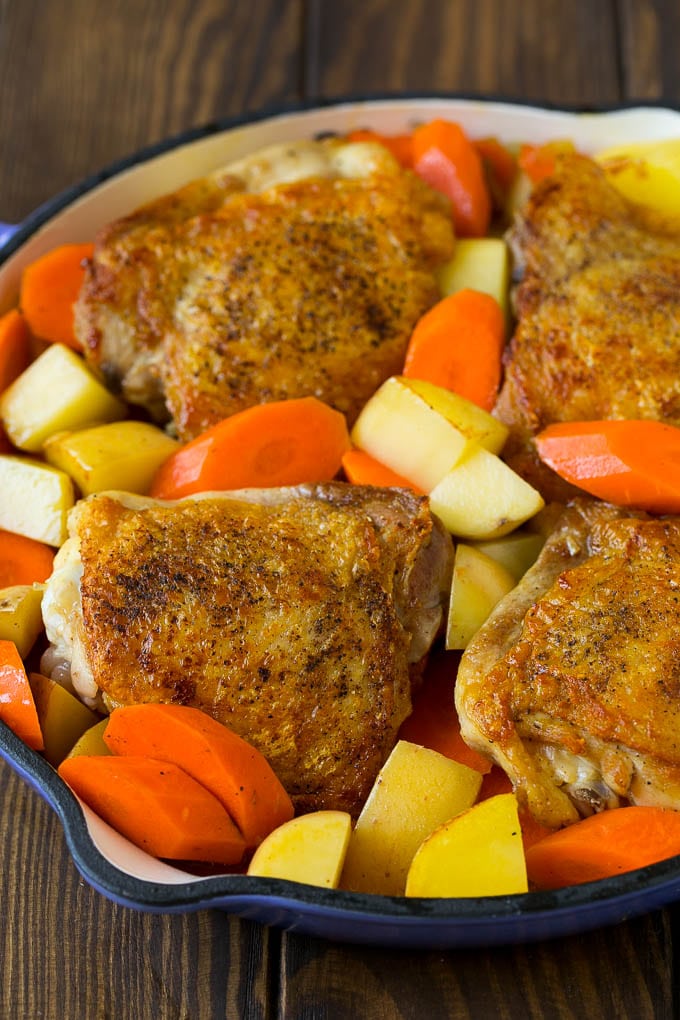 Chicken thighs, carrots and potatoes in a blue pan.