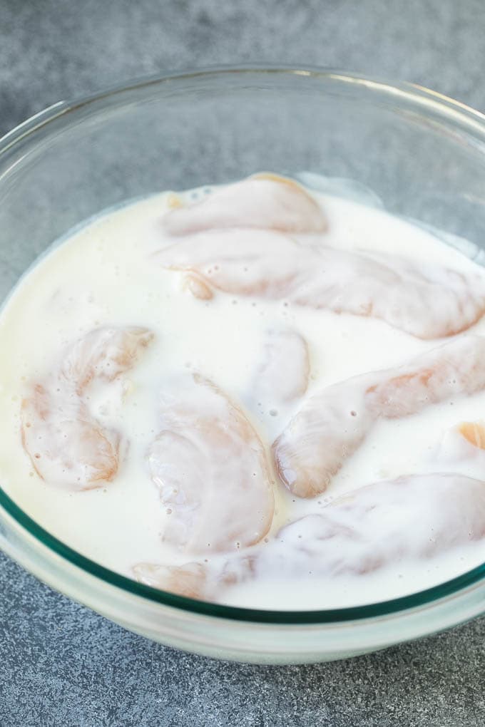 Chicken tenders in a bowl of buttermilk.
