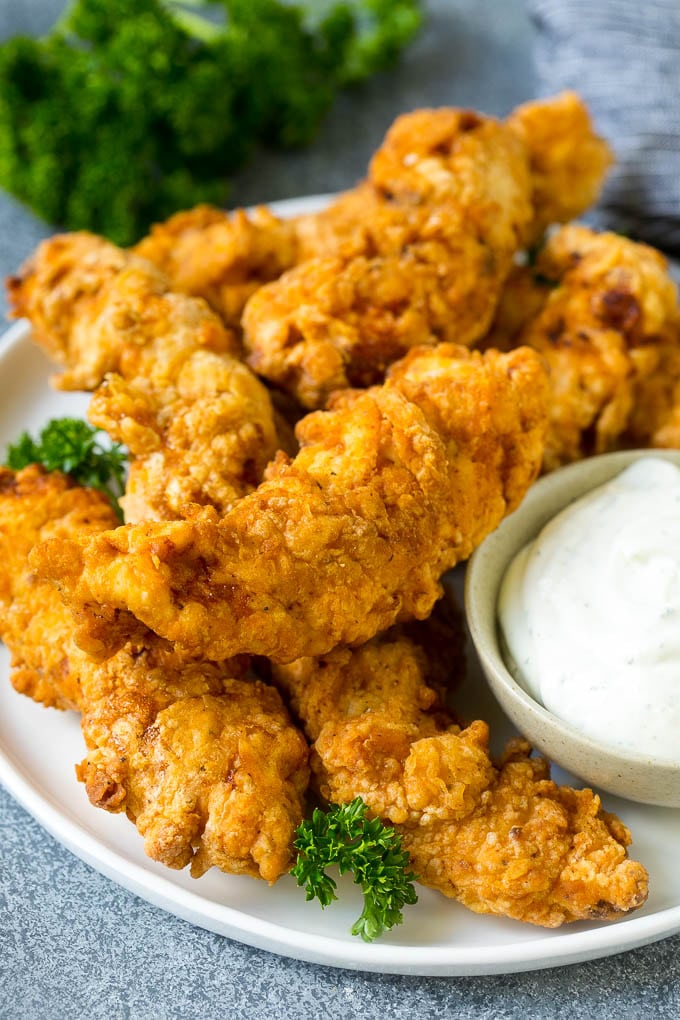 Chicken fingers on a serving plate with a side of ranch.