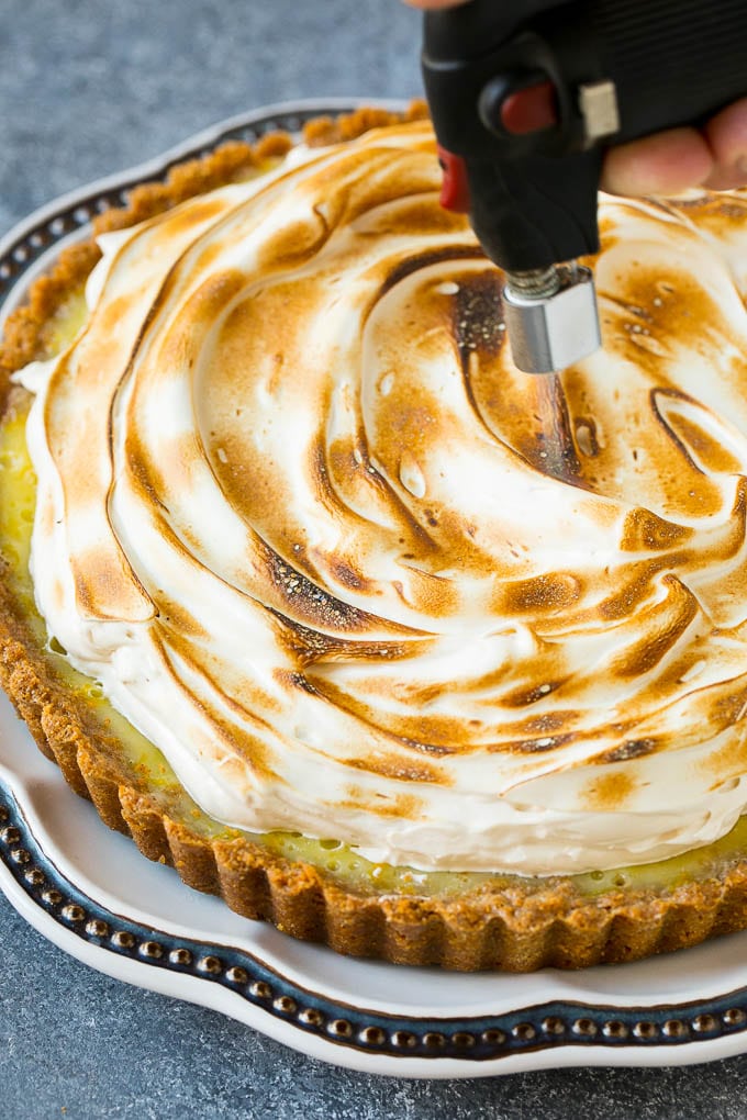 A torch browning meringue on top of a lemon tart.