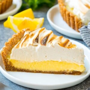 A slice of lemon meringue tart with creamy lemon filling and brown sugar meringue topping.