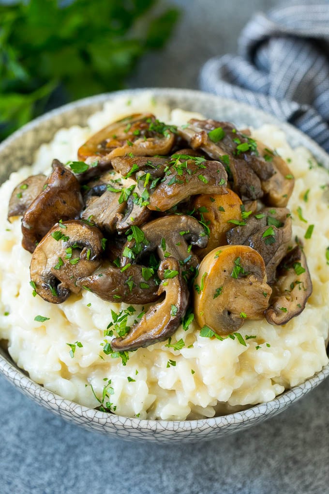 A bowl of mushroom risotto topped with garlic butter mushrooms.