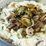 A skillet of mushroom risotto topped with seared mushrooms and parsley.