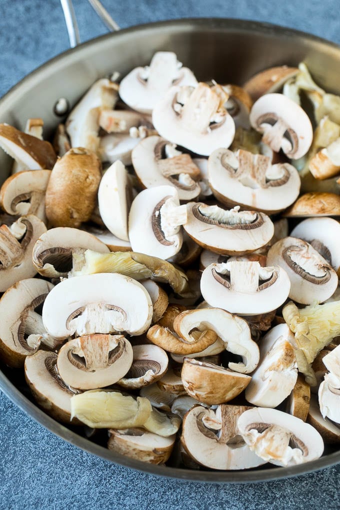 Sliced raw mushrooms in a skillet.
