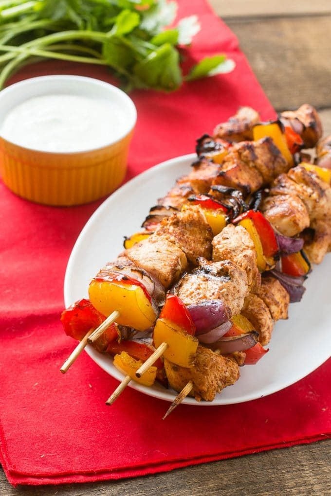 A plate of chicken fajita kabobs served with cilantro sauce.