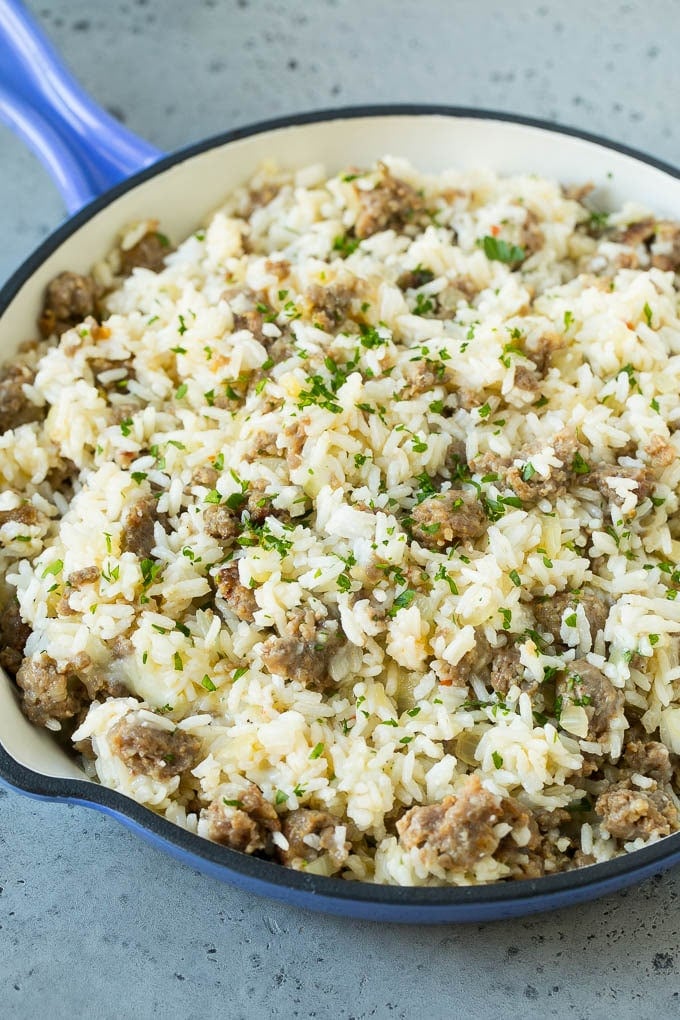 A mixture of cooked rice, sausage and cheese in a skillet.