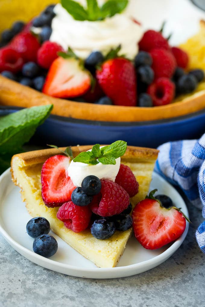 A slice of Dutch baby pancake topped with berries and whipped cream.