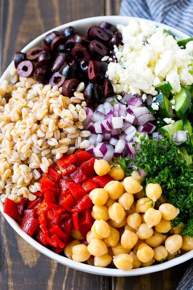 Cooked farro, roasted peppers, chickpeas, herbs, and olives in a bowl.