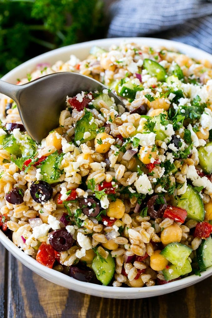 A bowl of farro salad with a serving spoon in it.