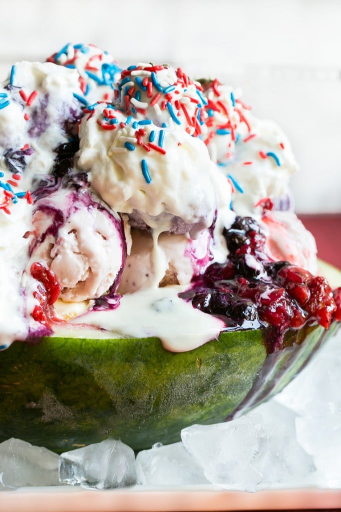 This recipe for a Red White and Blueberry Sundae is a watermelon loaded with three types of ice cream, homemade strawberry and blueberry sauces, marshmallow topping and the whole thing is finished off with whipped cream, sprinkles and chocolate covered strawberries. It's the perfect show stopper for the 4th of July!