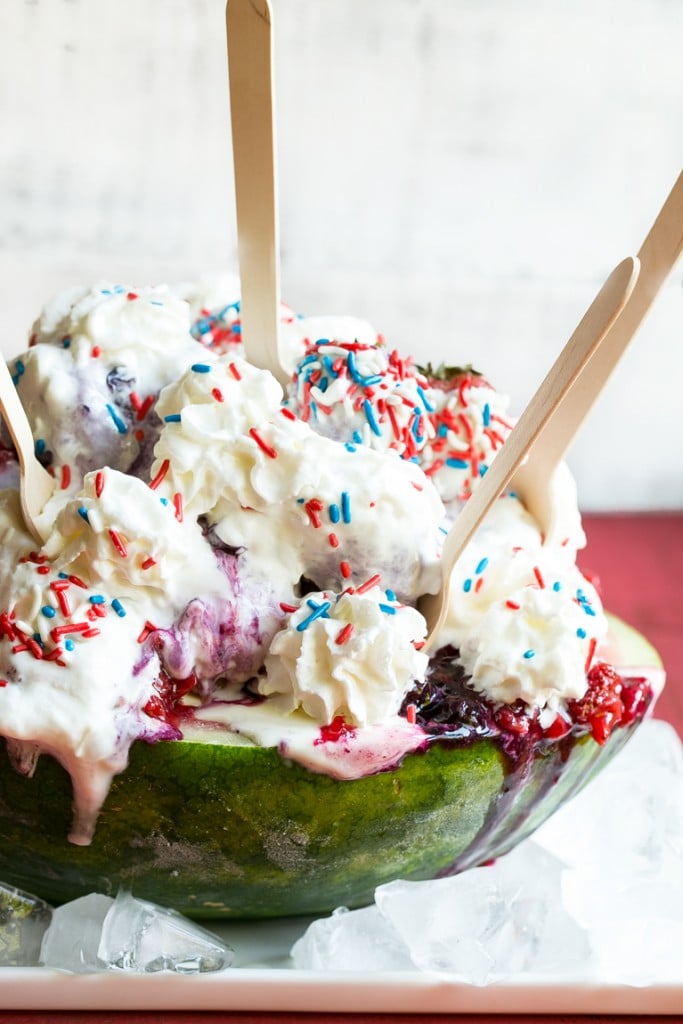 This recipe for a Red White and Blueberry Sundae is a watermelon loaded with three types of ice cream, homemade strawberry and blueberry sauces, marshmallow topping and the whole thing is finished off with whipped cream, sprinkles and chocolate covered strawberries. It's the perfect show stopper for the 4th of July!