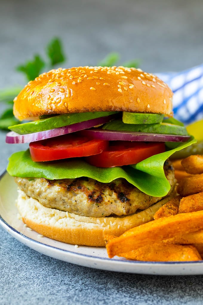 A turkey burger topped with lettuce, tomato, pickles and onion.