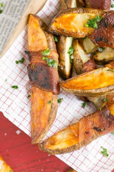 Bacon wrapped potatoes on a serving tray, topped with parsley.