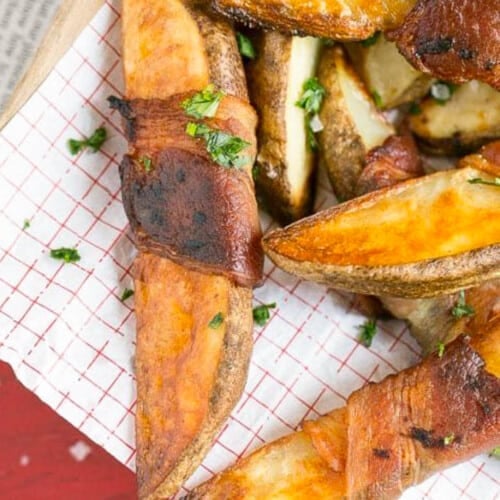 Bacon wrapped potatoes on a serving tray, topped with parsley.