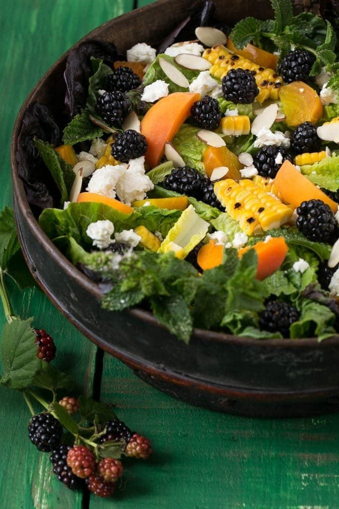 A salad bowl filled with lettuce, fresh produce, cheese and almonds.