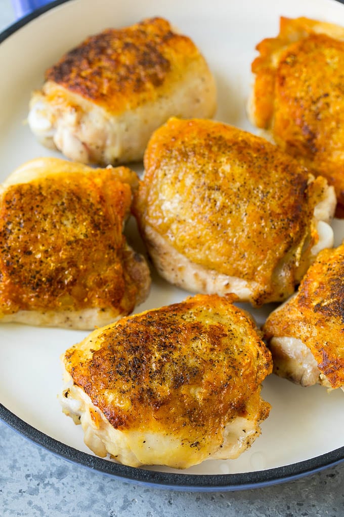 Browned chicken thighs in a pan.