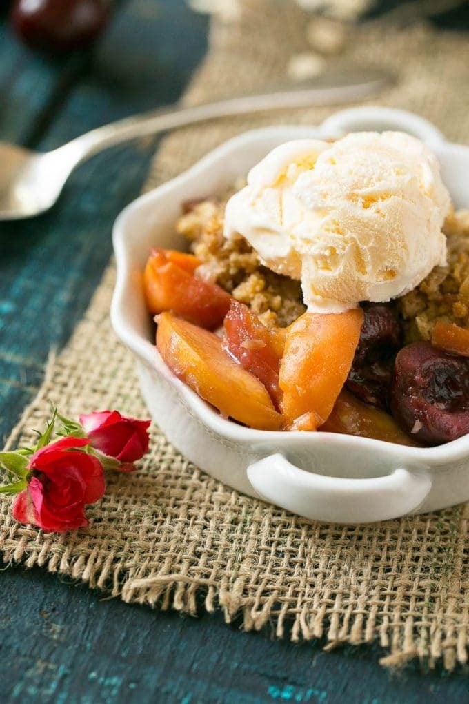 A bowl of fruit crisp topped with vanilla ice cream.