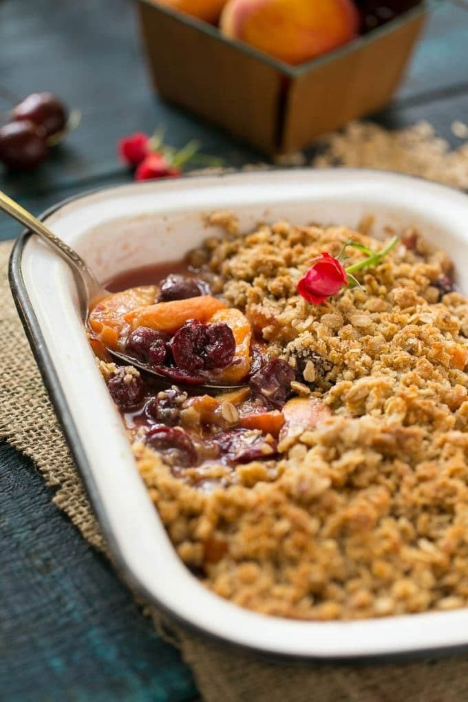 A serving spoon in a pan of fruit crisp.