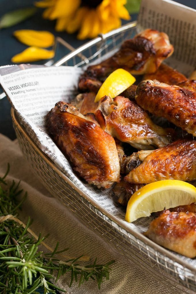 Baked chicken wings with lemon wedges in a serving basket.