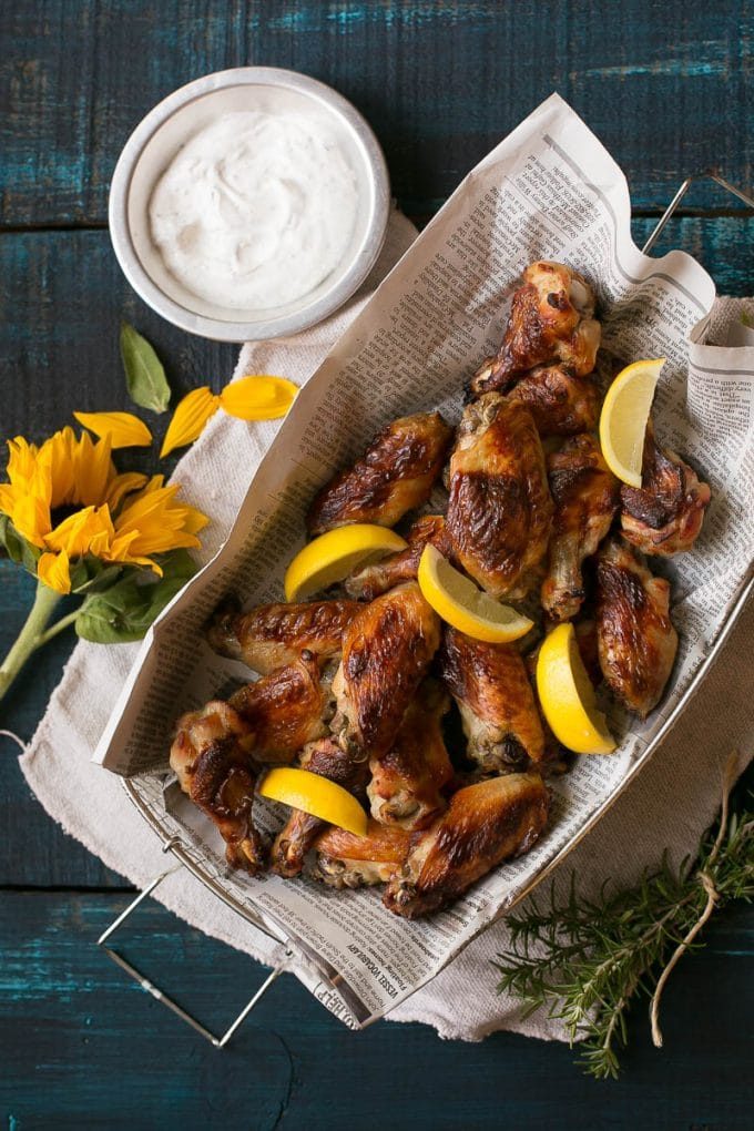 A basket of baked lemon chicken wings with a side of ranch.
