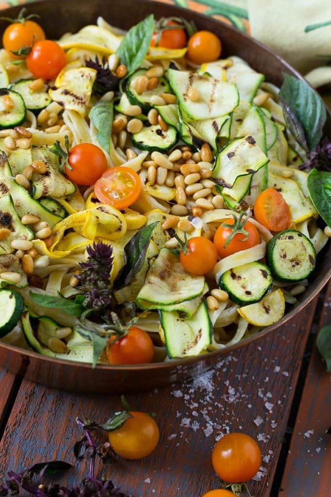 Pasta in a creamy sauce topped with vegetables and pine nuts.