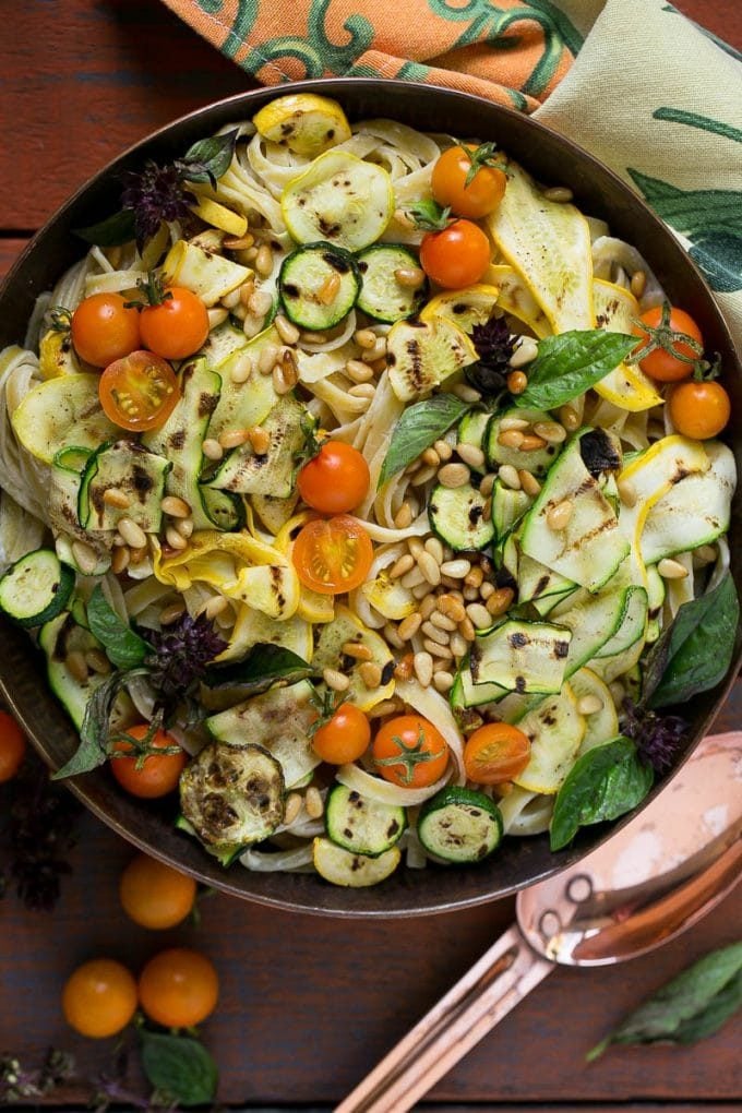 A serving bowl of zucchini fettuccine alfredo topped with cherry tomatoes.