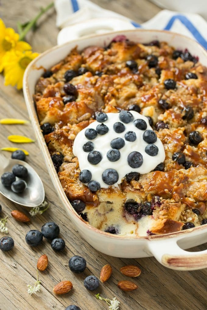 A pan of blueberry bread pudding topped with streusel and caramel sauce.