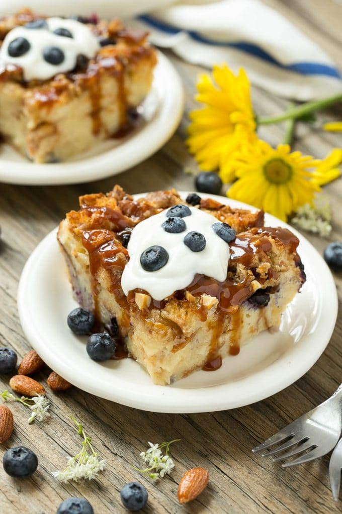 Slices of bread pudding on plates, topped with caramel and fresh berries.