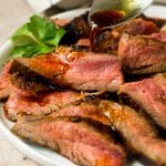 Flank steak marinade being drizzled over meat.