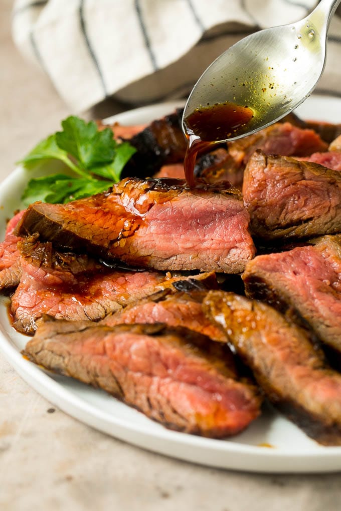 Flank steak marinade being drizzled over meat.