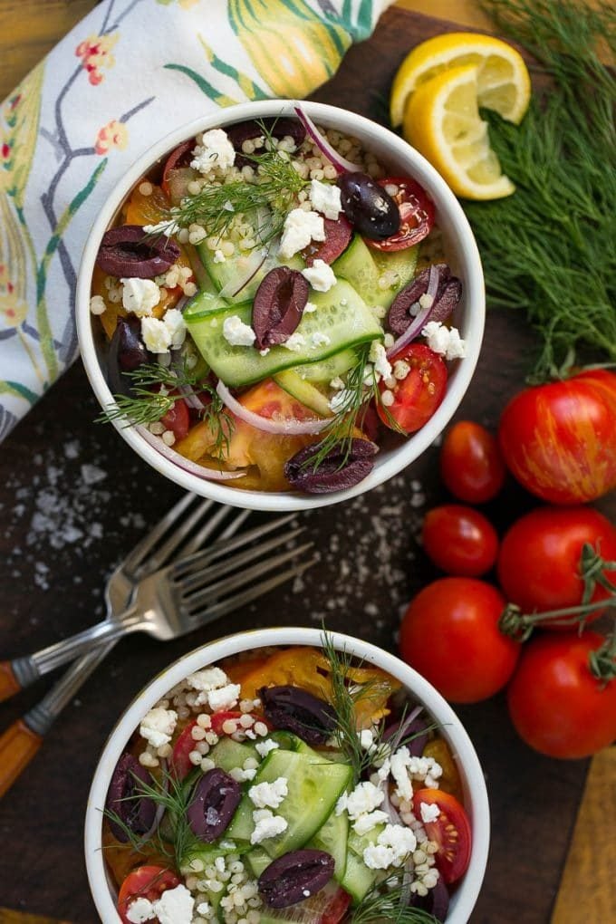 Bowls of Greek couscous with cucumber, olives and tomatoes.