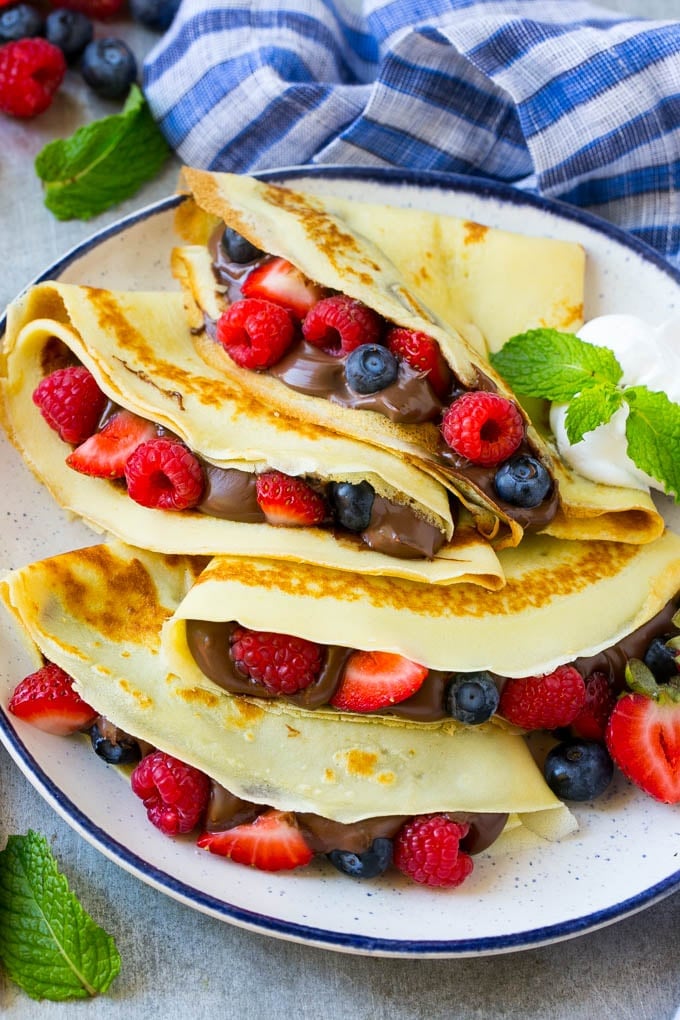 A platter of crepes served with whipped cream.