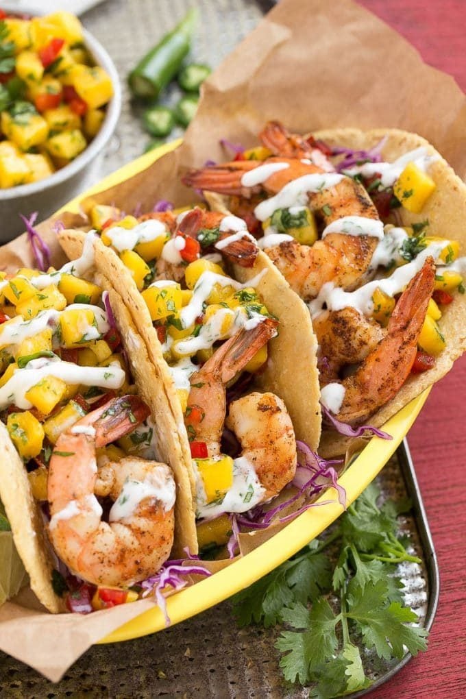 Three tacos filled with shrimp and a mango salsa.