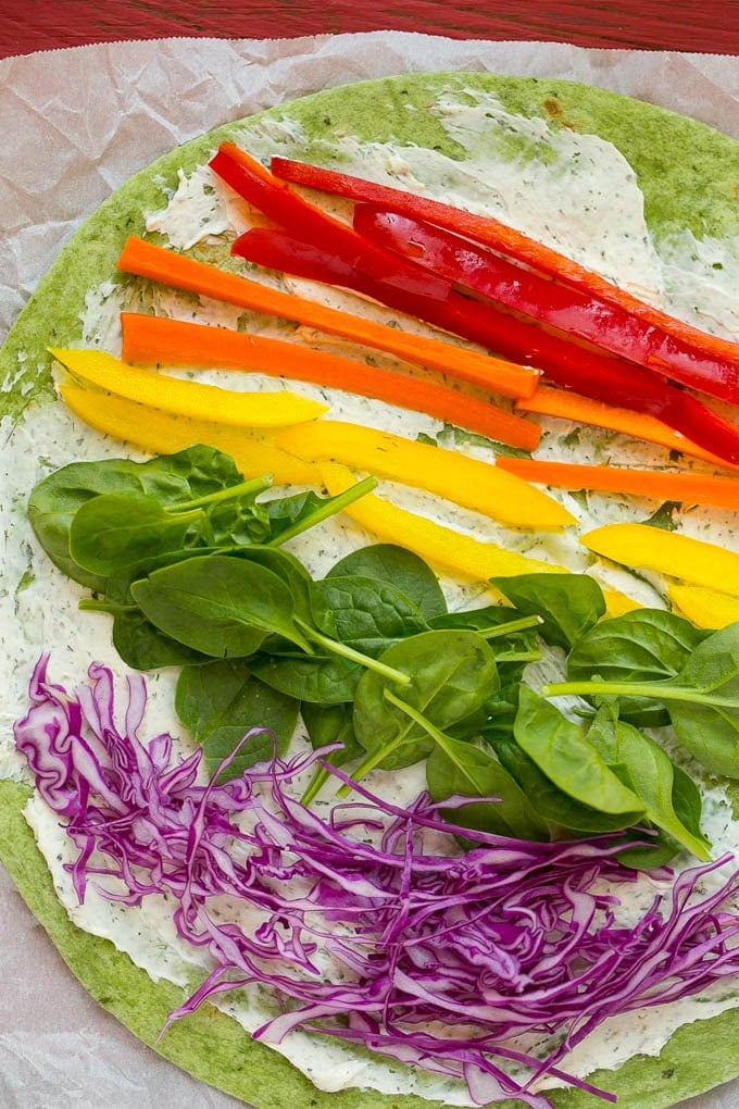 A spinach tortilla with layers of rainbow colored veggies.