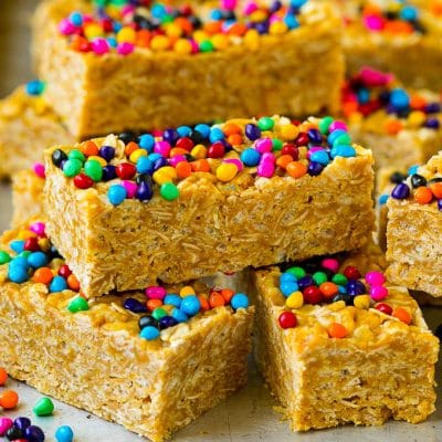 Cereal bars stacked on a sheet pan topped with colorful sprinkles.