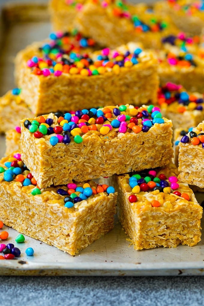Cereal bars stacked on a sheet pan topped with colorful sprinkles.