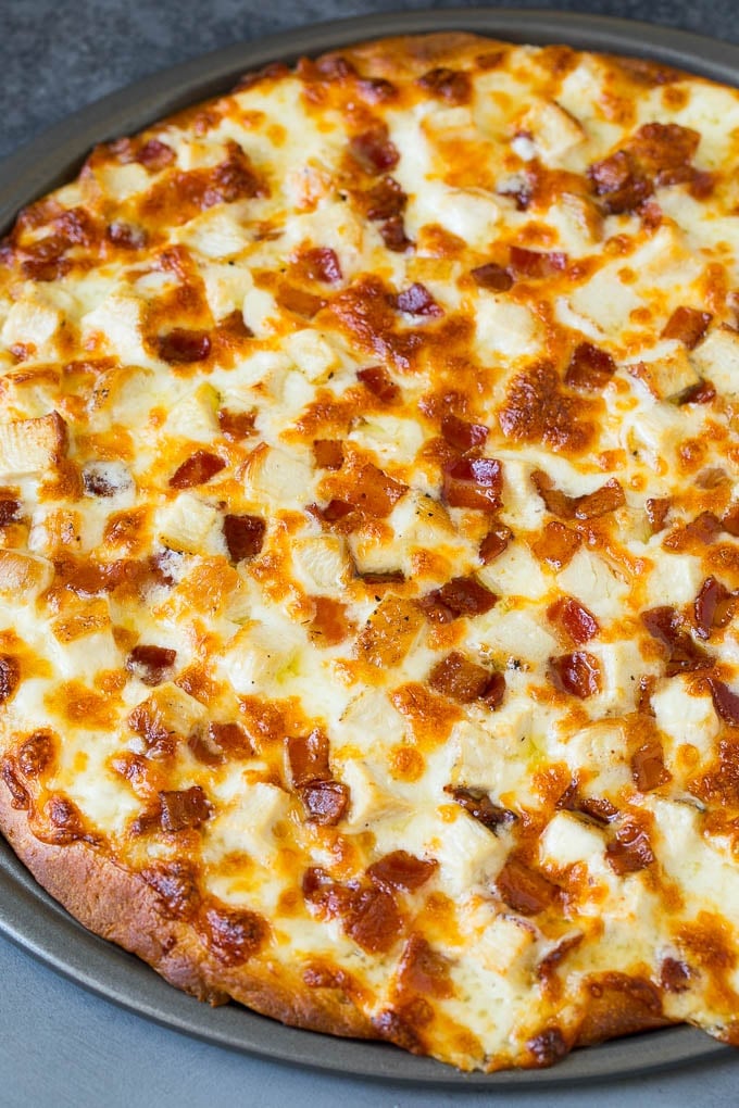A baked pizza topped with diced chicken and bacon.