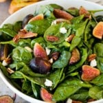 A bowl of fig salad with spinach, goat cheese and pecans.