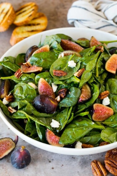 A bowl of fig salad with spinach, goat cheese and pecans.