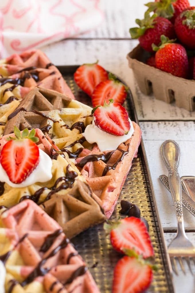 Strawberry chocolate waffles topped with whipped cream and berries.