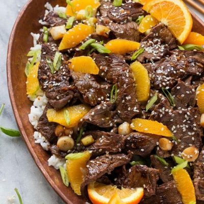 Orange beef in a pan served over rice.