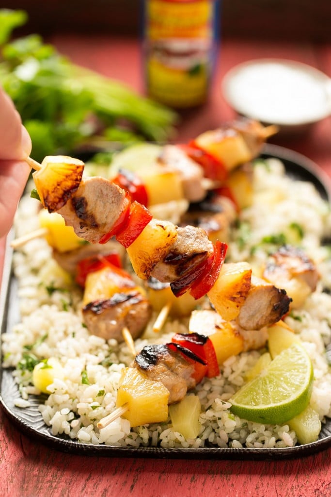 A plate of pork kabobs with pineapple and red bell peppers.